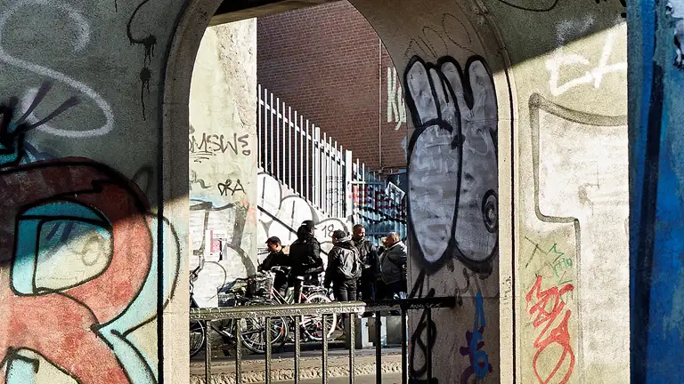 Gruppe af mænd under bro - graffiti på broen