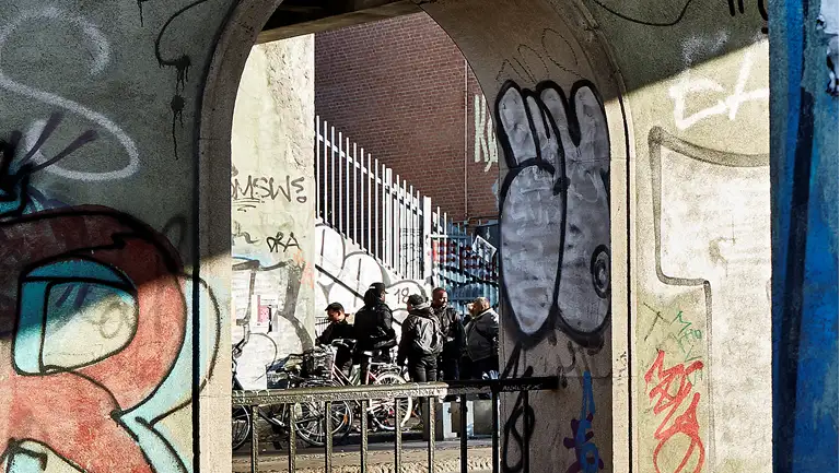 Gruppe af mænd under bro - graffiti på broen